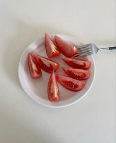 a white plate topped with sliced tomatoes and a fork