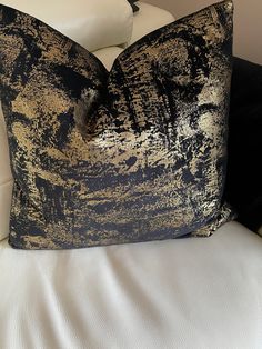 a black and gold pillow sitting on top of a white couch