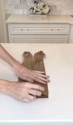 two hands that are on top of a white counter and one is holding something in the other hand