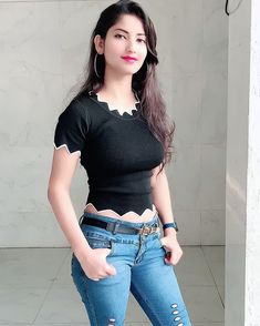 a young woman posing for the camera with her hands in her pockets and wearing ripped jeans