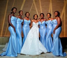 a group of women standing next to each other wearing blue dresses and posing for the camera