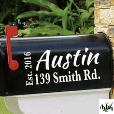 a black mailbox with the name aussie on it is next to a brick wall