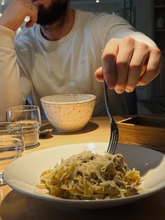 a man sitting at a table with a plate of food in front of him and a bowl of soup to the side