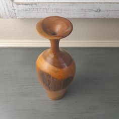 a small wooden vase sitting on top of a table next to a window sill