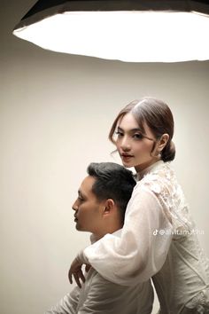 a woman sitting on top of a man's shoulder in front of a light