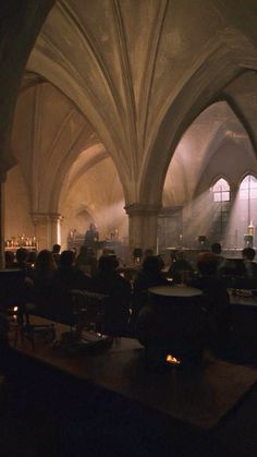 people sitting at tables in a dimly lit room with arches and columns on the walls