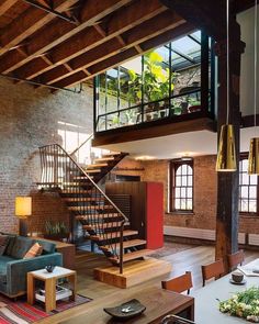 a living room filled with furniture and a spiral stair case next to a brick wall