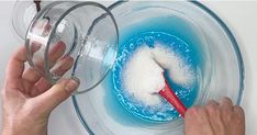 someone is mixing something in a bowl with a red spoon to stir it into blue liquid