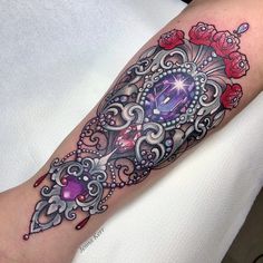 a woman's arm with a purple and red tattoo design on her left arm