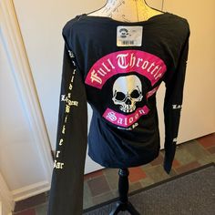 a black long sleeved shirt with pink and white skull on the front that says full strength saloon