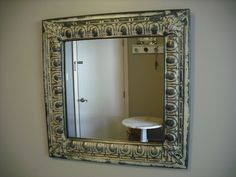 a mirror reflecting the reflection of a table in a room with a white wall and door