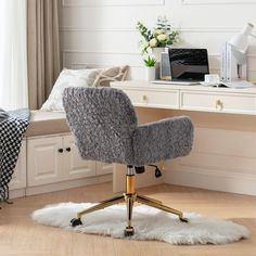 a desk with a chair, laptop and flowers on it in front of a window