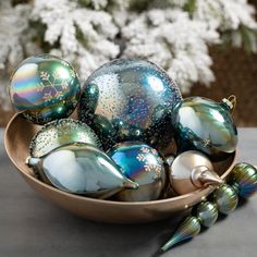 a bowl filled with shiny glass ornaments on top of a table