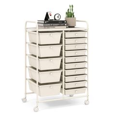 a white storage cart with many drawers on wheels and some plants in the top drawer