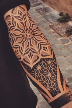 a man with a tattoo on his arm and hand is standing in front of a brick walkway