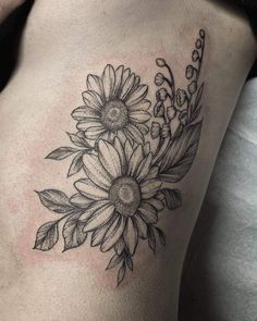 a black and white photo of a woman's thigh with flowers on the side