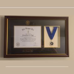 a framed award plaque with a blue ribbon and gold medal hanging on the wall next to it