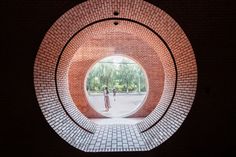 a brick tunnel with two people walking in it and one person standing on the other side