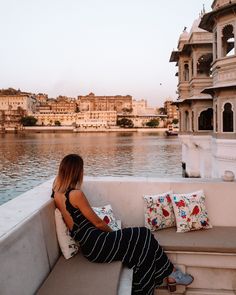 a woman sitting on the edge of a boat in front of a body of water