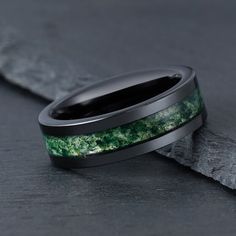 a wedding band with green and black stone inlays on the inside of it