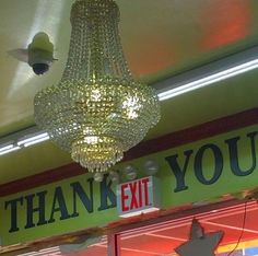 a chandelier hanging from the ceiling in front of a sign that says thank you