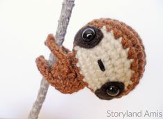 a crocheted sloth hanging from a tree branch