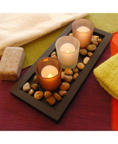 three candles are sitting on a tray with rocks