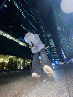 a person in grey pants and hoodie standing on the sidewalk with their feet up