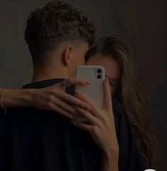 a man and woman embracing each other with their cell phones