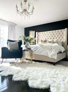 a bedroom with black walls, white fur rugs and a chandelier hanging from the ceiling