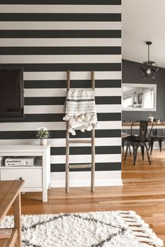 a living room with black and white stripes on the wall next to a tv set