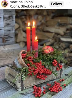 some red berries and candles are in a wooden box