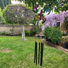 a wind chime in the middle of a yard next to a tree with purple flowers