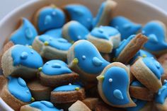 a white bowl filled with blue and yellow decorated cookies