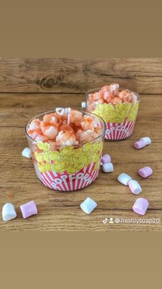 two cups filled with candy and marshmallows on top of a wooden table