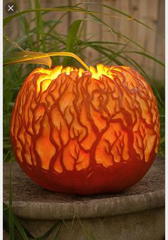 an orange carved pumpkin sitting on top of a cement slab with fire coming out of it