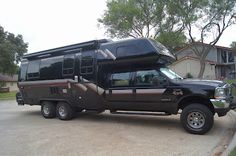 a black truck with a camper on the bed is parked in front of a house