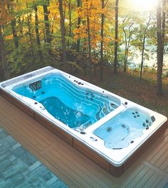 a hot tub sitting on top of a wooden deck next to a wooded area with trees