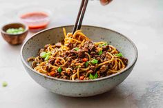 a bowl filled with noodles, meat and veggies on top of a table