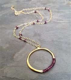 This item is made to order please allow 5 to 8 business days for your order to ship. This circle necklace was This necklace measures 16 inches in length and has a 2 inch extension chain for easy adjusting. The gold filled chain is intertwined with faceted rhodolite rondelle beads, the circle is completely handmade from 0.925 sterling silver followed by a heavy 14k gold plating and finished with genuine rhodolite rondelle beads. Burgundy Garnet Round Jewelry, Round Burgundy Garnet Jewelry, Round Garnet Gemstone Necklaces, Ruby Jewelry With Faceted Round Beads, Round Faceted Ruby Beads Jewelry, Ruby Jewelry With Faceted Beads, Round Ruby Jewelry With Faceted Beads, Gold Garnet Round Pendant Jewelry, Round Ruby Necklace With Faceted Beads