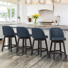 three blue stools sit at the center of a kitchen island in front of an oven