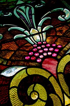 a close up view of a stained glass window with flowers and swirls on it