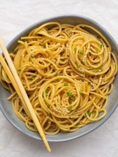 a bowl filled with noodles and chopsticks on top of a white tablecloth