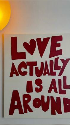 a red and white sign that says love actually is all around on the side of a wall