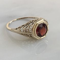 Details: Stunning Art Deco Period garnet and 14K white gold filigree ring! The stone measures 6mm, and the is 5.6mm above the finger at the highest point on the ring. The filigree is beautiful on this ring, and is in lovely shape. This is a stunning ring--you will not be disappointed! Please ask all necessary questions prior to placing an order. Measurements: The size is 5 US and can be sized for a fee. Condition: The overall all condition of this ring is very good. Elegant Hallmarked Garnet Birthstone Ring, Elegant Yellow Gold Ruby Ring With Intricate Design, Victorian 14k Gold Ruby Ring With Intricate Design, 14k Gold Filigree Ruby Ring Gift, Elegant 14k Gold Ruby Ring With Intricate Design, 14k Gold Ruby Ring With Filigree For Gift, Wedding Rings With Intricate Garnet Design, Anniversary Ruby Ring With Intricate Design, Antique Ruby Filigree Ring