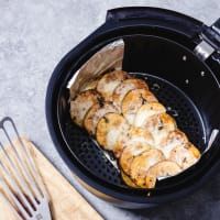 the food is being cooked in an air fryer with tongs next to it