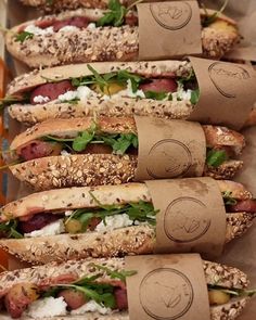 several sub sandwiches with different toppings are lined up in a row on the table