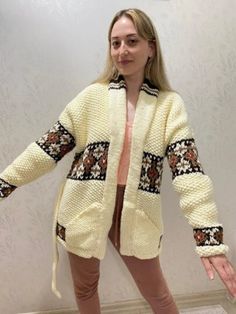 a woman standing in front of a wall with her hands out to the side, wearing a sweater and leggings