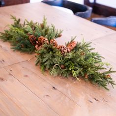 a wooden table topped with pine cones and greenery