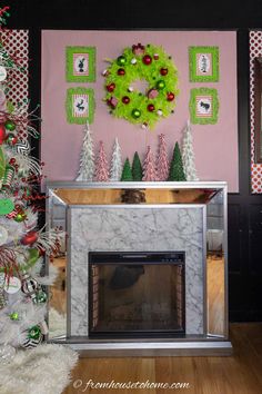 a decorated christmas tree in front of a fireplace with a wreath on the wall above it